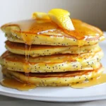To make Lemon Poppy Seed Pancakes, you need these key ingredients: - 1 cup all-purpose flour - 1 tablespoon poppy seeds - 2 teaspoons baking powder - ¼ teaspoon salt - 2 tablespoons granulated sugar - 1 cup milk - 1 large egg - 2 tablespoons melted butter (plus more for cooking) - Zest of 1 lemon - 2 tablespoons fresh lemon juice These ingredients create a fluffy base with a bright lemon flavor. The poppy seeds add a nice crunch and visual appeal. You can enhance your pancakes with these optional ingredients: - Vanilla extract for a sweet touch - Fresh blueberries or raspberries for a fruity burst - A sprinkle of cinnamon for warmth These additions can make your pancakes even more delicious and fun! Accurate measuring is key for great pancakes. Here are some tips: - Use a dry measuring cup for flour. Spoon the flour in and level it off. - For liquid ingredients, use a clear measuring cup. Check the level at eye height. - When measuring sticky ingredients like honey, spray the cup with cooking oil first. Following these tips will help you get the right texture and flavor in your pancakes. {{ingredient_image_2}} Start by gathering your dry ingredients. You will need: - 1 cup all-purpose flour - 1 tablespoon poppy seeds - 2 teaspoons baking powder - ¼ teaspoon salt - 2 tablespoons granulated sugar In a medium bowl, mix the flour, poppy seeds, baking powder, salt, and sugar. Whisk these well until there are no lumps. This step helps your pancakes rise and stay fluffy. Now, let’s move on to the wet ingredients. You will need: - 1 cup milk - 1 large egg - 2 tablespoons melted butter (plus more for cooking) - Zest of 1 lemon - 2 tablespoons fresh lemon juice In a separate bowl, combine the milk, egg, melted butter, lemon zest, and lemon juice. Whisk these together until smooth. This mixture adds flavor and moisture to your pancakes. Next, we combine the wet and dry mixtures. Gradually pour the wet mix into the dry ingredients. Use a spatula or wooden spoon to gently stir. Stop mixing when you see a few small lumps. This is key for keeping the pancakes fluffy! Preheat your non-stick skillet or griddle over medium heat. Add a small dab of butter to coat the surface. For each pancake, pour about ¼ cup of batter into the skillet. Cook until bubbles form and edges look set, around 2-3 minutes. Carefully flip the pancakes with a spatula. Cook the other side for another 2-3 minutes until golden brown. Repeat this until all the batter is used, adding more butter as needed. Serve your pancakes warm. Drizzle them with maple syrup or honey for a sweet touch. For a fun presentation, stack them high and top with lemon slices or a sprinkle of poppy seeds. A dollop of whipped cream can make them even more special! To keep your pancakes fluffy, mix them gently. Combine the wet and dry ingredients until just mixed. It's okay to have some small lumps. Overmixing can lead to tough pancakes. Remember, less is more when it comes to mixing! For golden brown pancakes, heat your skillet to medium. Add a little butter before cooking. Pour about ¼ cup of batter for each pancake. Cook until bubbles form on top, then flip carefully. The perfect flip is key. Cook the other side until golden, about 2-3 minutes more. If you have leftover pancakes, store them right. Let them cool completely first. Place them in an airtight container. You can refrigerate them for up to three days. For longer storage, freeze them in layers with parchment paper. This keeps them from sticking together. Reheat them in a toaster or microwave when ready to eat. Enjoy them warm with syrup! Pro Tips Use Fresh Ingredients: Always opt for fresh lemons and high-quality milk to enhance the flavor of your pancakes. Freshness makes a noticeable difference in taste! Monitor Heat Levels: Keep your skillet at medium heat and adjust as necessary. Too high can burn the pancakes, while too low may leave them soggy. A steady temperature ensures golden brown results. Perfect Fluffiness: To achieve extra fluffy pancakes, let the batter rest for about 5 minutes after mixing. This allows the baking powder to activate and create air pockets in the batter. Experiment with Toppings: Don't hesitate to get creative with your toppings! Fresh berries, yogurt, or even a sprinkle of coconut can elevate your pancake experience. {{image_4}} You can make your lemon poppy seed pancakes even better by adding fruits and nuts. Fresh blueberries or raspberries bring a sweet burst to each bite. You can mix in about half a cup of these berries right into the batter. Chopped nuts, like walnuts or pecans, add a nice crunch. Try adding a quarter cup of nuts to the mix. Just fold them in gently to keep the batter fluffy. If you want to make these pancakes vegan or dairy-free, it’s easy! Swap the milk for almond or oat milk. You can replace the egg with a flaxseed egg. To make a flaxseed egg, mix one tablespoon of ground flaxseed with three tablespoons of water. Let it sit for about five minutes until it thickens. Use coconut oil instead of butter for a dairy-free option. Experimenting with different zests can add fun flavors to your pancakes. Try orange or lime zest for a twist. Just use the same amount as you would for lemon zest. This small change can create a new taste that still feels fresh and bright. You can even mix zests for a unique flavor combo. Just remember to adjust the amount of lemon juice, so the batter stays balanced. To keep your pancakes fresh, store them in the fridge. Let them cool first. Place the pancakes in an airtight container. You can also use plastic wrap. They will last for about three days in the fridge. When you are ready to eat, just reheat them. If you want to save pancakes for later, freezing is a great option. Stack the pancakes with parchment paper between each one. This prevents them from sticking together. Then, wrap the stack tightly in plastic wrap. Place it in a freezer bag. These pancakes can last for about two months in the freezer. To reheat, pop them in the toaster or microwave. Heat them until warm, and they will taste fresh again. Meal prep makes mornings easier. You can make a big batch of pancakes on the weekend. Store them in the fridge or freezer as mentioned. When you want pancakes, just reheat them. You can even add toppings like syrup or fruit before storing. It saves time and makes breakfast fun! Yes, you can make pancakes without eggs. Try using applesauce or mashed banana as a substitute. Use about ¼ cup of either per egg. They help bind the batter and add moisture. You can also mix ground flaxseed with water. This creates a gel-like mix that works well in pancakes. Pancakes are done when they are golden brown on both sides. Look for bubbles on the surface before flipping them. The edges should look set, not wet. If you press gently, they should spring back. This means they are fluffy and cooked well. You can add many tasty toppings. Fresh berries like blueberries or strawberries pair nicely. A dollop of whipped cream adds richness. You can also sprinkle more poppy seeds for crunch. Try drizzle honey or maple syrup for sweetness. A bit of lemon zest on top brightens the dish. Yes, you can use whole wheat flour instead of all-purpose flour. This makes the pancakes heartier and adds fiber. The texture will be a bit denser, but they will still taste great. You might need to add a little more milk to keep the batter smooth. In this post, we explored how to make delicious pancakes. We covered essential and optional ingredients, plus tips for measuring. You learned the steps for preparing, mixing, and cooking pancakes for fluffiness. I shared tips to get that golden brown color and ways to store leftovers. We also talked about fun variations, like adding fruits or going vegan. Use this guide to make pancakes you and your family will love. Enjoy the process, and happy cooking!